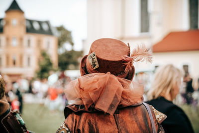 Rear view of woman wearing hat standing in city