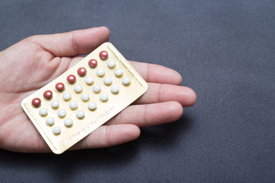 Close-up of hand holding blister pack on table