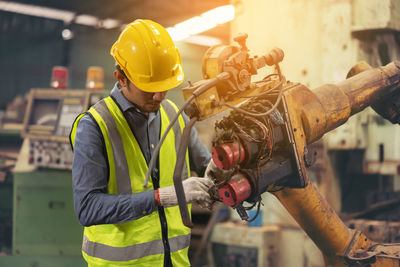 Engineers in an industry plant setting up machines vs a background of a machine factory.