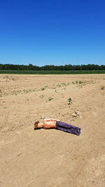 Man standing on sand against clear blue sky