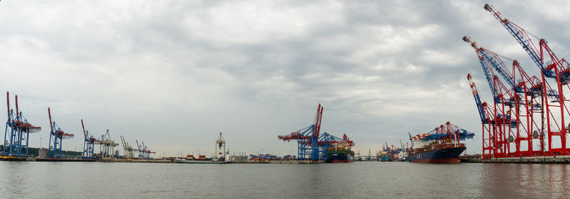 Cranes at commercial dock against sky