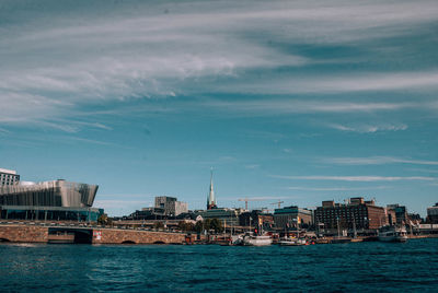 Sea by buildings against sky in city