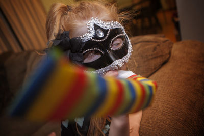 Close-up of girl wearing mask on sofa at home