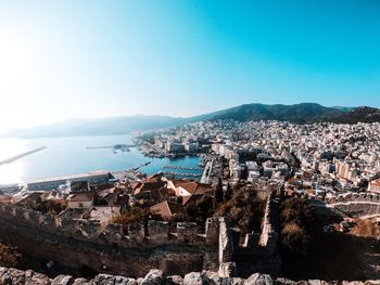 Aerial view of townscape by sea against clear sky