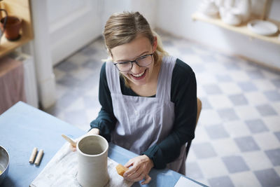 High angle view of smiling woman learning pottery in art class