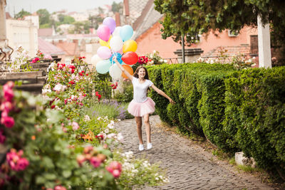 Rear view of woman standing on pink flowering plants