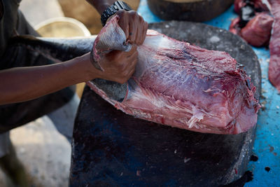 Fish vendor skinning fresh raw tuna fish at seafood market