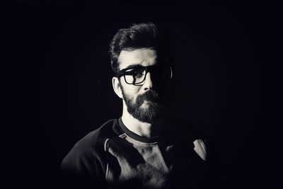 Young man wearing eyeglasses against black background