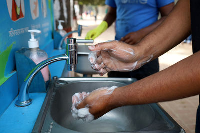 Cropped image of hand touching water from faucet at home