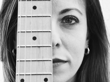 Close-up portrait of woman looking through guitar