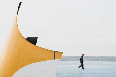 Side view full length of manual worker walking by lake on roof