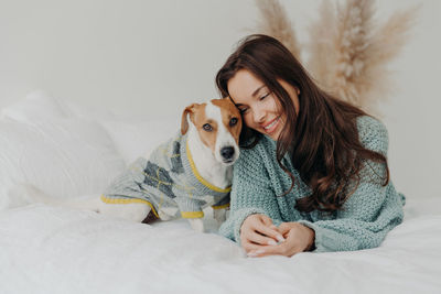 Smiling woman with dog relaxing on bed