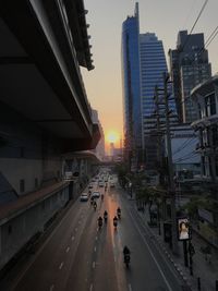 City street amidst buildings against sky during sunset