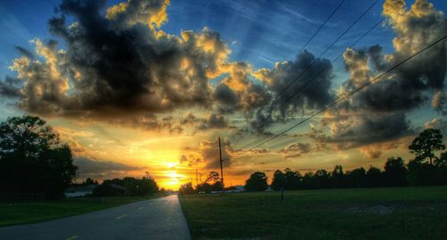 Scenic view of field against cloudy sky at sunset