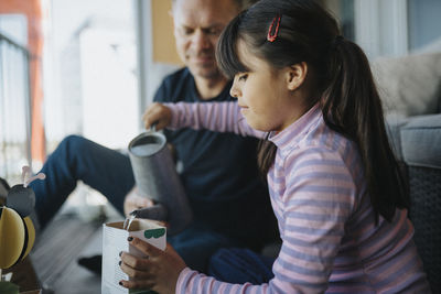 Father and daughter bonding over planting seedlings on balcony