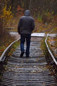 Full length rear view of man walking on train tracks