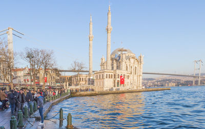 View of boats in canal by buildings against clear sky