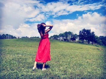 Woman in red dress standing on field.