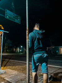 Rear view of man standing on street at night