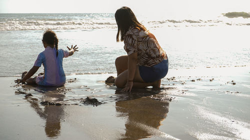 Rear view of women sitting on beach