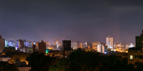 Illuminated buildings in city against sky at night