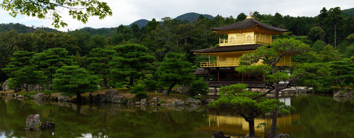 Temple by lake and trees against sky