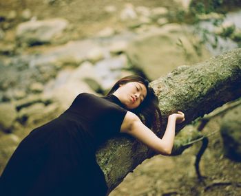 Woman sleeping on tree trunk in forest