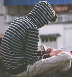 Side view of man using mobile phone on building terrace