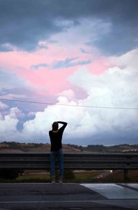 Man standing on landscape against cloudy sky
