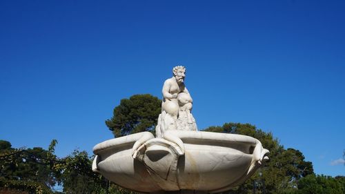 Low angle view of statue against clear blue sky in park