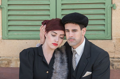 Serious couple sitting against wall