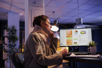 Side view of man using laptop while standing in city