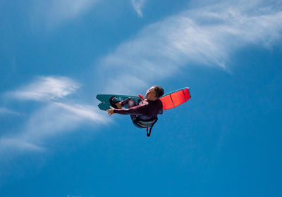 Low angle view of man surfboarding against blue sky