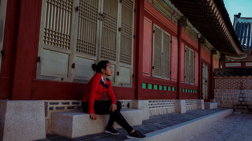 Full length of young woman sitting outdoors