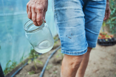 Midsection of woman holding container with water