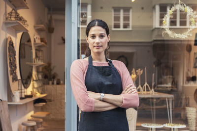 Confident female owner with arms crossed outside store