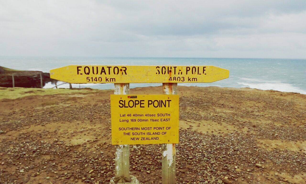 text, western script, communication, information sign, sign, sky, sea, warning sign, non-western script, beach, guidance, horizon over water, capital letter, yellow, water, information, shore, tranquility, nature, sand