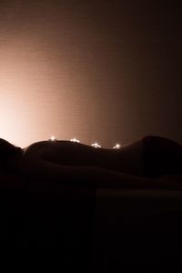 Silhouette of lying down on bed against wall