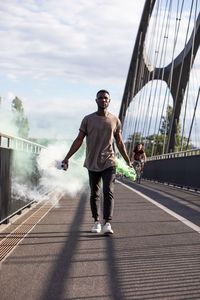 Man walking on bridge in city against sky