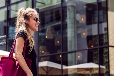 Low angle view of smiling young woman walking in city