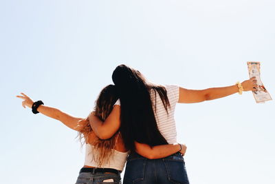 Rear view of women standing against clear sky