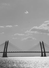 Bridge over calm sea against cloudy sky