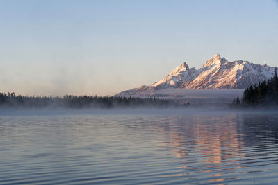 Scenic view of lake by snowcapped mountain against sky