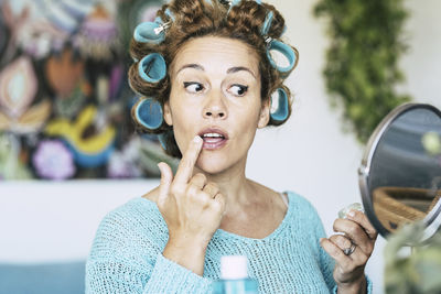 Close-up of woman applying lipstick looking at hand mirror