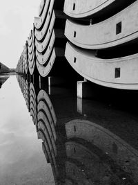 Low angle view of stacked concrete blocks reflecting in water on ground against sky