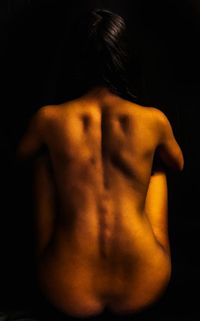 Rear view of shirtless man against black background