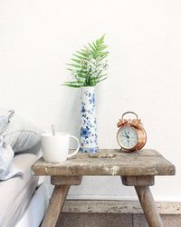 Clock and vase on wooden table against wall