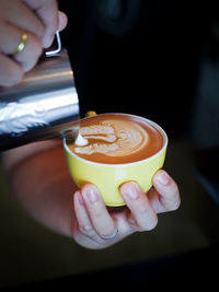 Close-up of hand making coffee in cup