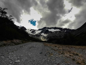 Scenic view of road by mountains against sky