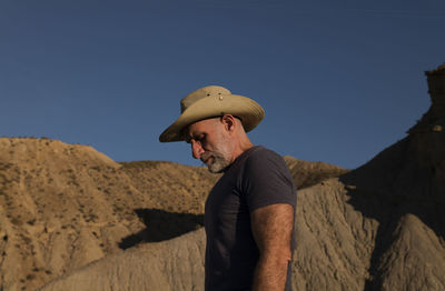 Adult man in cowboy hat on desert against mountain. almeria, spain